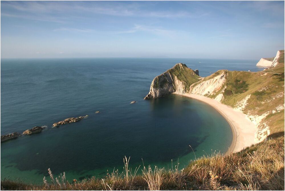 Дорога к  Durdle Door. Многокилометровая береговая полоса имеет постоянный скалистый ландшафт. Всю картину можно увидеть на карте со спутника. Довольно дикая местность получила название в Англии Jurassic Coast. Пляжей нет и мест для отдыха там немного. Но уютные пабы встречаются, как и во всей Англии. Из-за крутых склонов West Lulworth нельзя назвать  комфортным местом для отдыха с детьми. Подходить к краю склона небезопасно.
На этой фотографии вид на бухту Man o'War cove