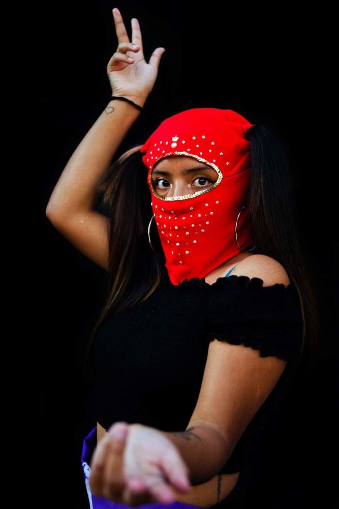 Baila Capucha Collective&rdquo;   Women from the &ldquo;Baila Capucha&rdquo; Collective pose with their red hoods to protect their identity due to fear of being imprisoned, discriminated or fired from work for participating in the protests held in the context of the social revolt against the neoliberal economic system and the government of Sebasti&aacute;n Pi&ntilde;era in Chile.  The Baila Capucha is a group of dissidents, self-organized women that dance with their faces covered by bright red and black hoods in order to remain anonymous and protect members while they express themselves by way of dance.  The feminist collectives in the protests of the social revolt played different roles. In addition to being at the heart of the changes demanded by women in terms of justice and work conditions, they also play a leading role in society.
