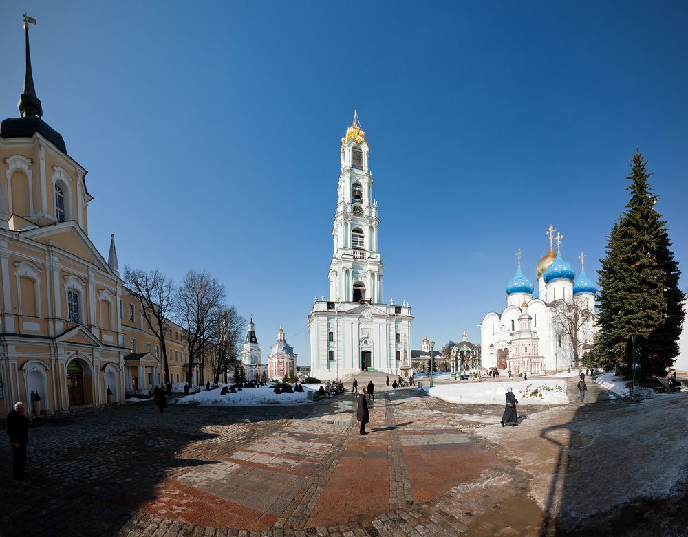 Вид на Колокольню (1741 &ndash; 1768) (в центре), Казначейский корпус братских келлий (1743 &ndash; 1745) (слева), Успенский кладезь с часовней (1644 г. &ndash; кон. XVII в.) и Успенский собор (1585) (справа). Колокольня Троице-Сергиевой Лавры, строившаяся с 1741 по 1768 г., замыкает собой северную сторону соборной площади. Высота колокольни составляет 88 м, что на 11 м больше звонницы Новодевичьего монастыря и на 6 м &ndash; колокольни Ивана Великого в Московском Кремле.     Окончательный архитектурный облик, благодаря которому лаврская колокольня получила заслуженную славу красивейшей на Руси, придал ей замечательный русский архитектор Д. В. Ухтомский. Пятиярусная колокольня, отличающаяся исключительной стройностью и изяществом, изысканностью убранства, является одним из лучших памятников русской архитектуры XVIII в.    Колокольня достойно завершила формирование уникального архитектурного лаврского ансамбля, став его высотной доминантой и объединив тем самым все другие архитектурные сооружения соборной площади.    На колокольне размещалось уникальное собрание лаврских колоколов, сильно пострадавшее в 1930 г., когда были разбиты 25 колоколов, в том числе и самый большой на Руси &ndash; Царь-колокол, весом 4 тыс. пудов (64 т.). Вес вновь отлитого в 2003 г. для лаврской колокольни Царь-колокола составляет 72 т. Трехэтажное здание Казначейского корпуса замыкает собой с запада соборную монастырскую площадь. В настоящее время фасад корпуса ограничен с севера Больничными палатами с церковью преподобных Зосимы и Савватия Соловецких, а с юга &ndash; пристроенной к нему трехэтажной Лестничной башней.    Фасад Казначейского корпуса получил свой нынешний, не слишком выразительный в архитектурном отношении, вид в 1858&ndash;1859 гг. и объединяет собой разновременные служебные постройки XVII&ndash;XIX в.    Ныне первый этаж здания отведен под административные помещения, а второй и третий &ndash; под братские келлии.