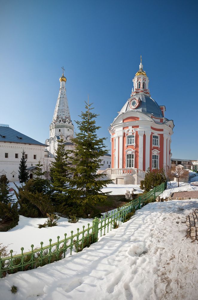 Церковь Смоленской иконы Божией Матери (1746 &ndash; 1753)    Церковь Смоленской иконы Божией Матери (Одигитрии) расположена за колокольней, напротив церкви преподобных Зосимы и Савватия Соловецких, и замыкает собой северо-западный угол соборной площади. Церковь сооружена в 1746 г. по проекту архитектора Д. В. Ухтомского и освящена в 1753 г.    Небольшой, круглый в плане, храм, завершенный гармоничной формы куполом и световым фонарем с миниатюрной фигурной главой и крестом, является прекрасным образцом архитектуры елизаветинского барокко, но с удивительным художественным тактом вписан в древний ансамбль монастыря.    Бирюзовые стены церкви украшены ритмически чередующимися белыми сдвоенными пилястрами и резными белокаменными обрамлениями двух ярусов окон. С четырех сторон храм окружают идущие вдоль его стен лестницы-всходы.     Первоначальный иконостас церкви, к сожалению, не сохранился. В настоящее время ее украшает замечательный резной иконостас из разобранной московской церкви Параскевы Пятницы, что на Пятницкой улице, выполненный в 1748 г. по проекту Д. В. Ухтомского.    Богослужения в церкви Смоленской иконы Божией Матери совершаются в ее престольный праздник (28 июля/10 августа) и в воскресные и праздничные дни (начало в 8 час. 20 мин.). В нише на восточной стене помещена резная каменная икона, копия главной святыни церкви &ndash; чудотворного монастырского образа Одигитрии, находящегося в настоящее время в Художественном музее.