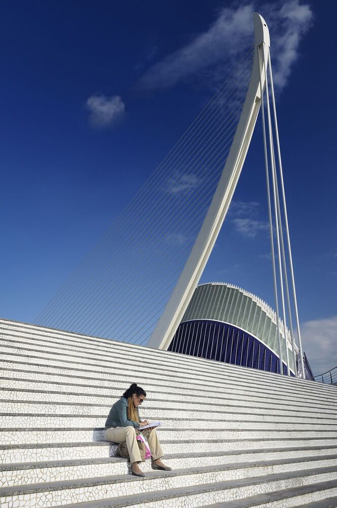 A lady reading her book on the steps of the "City of Arts and Sciences" in Valencia/Spain. This part of the city has a wonderful collection of very modern architecture.