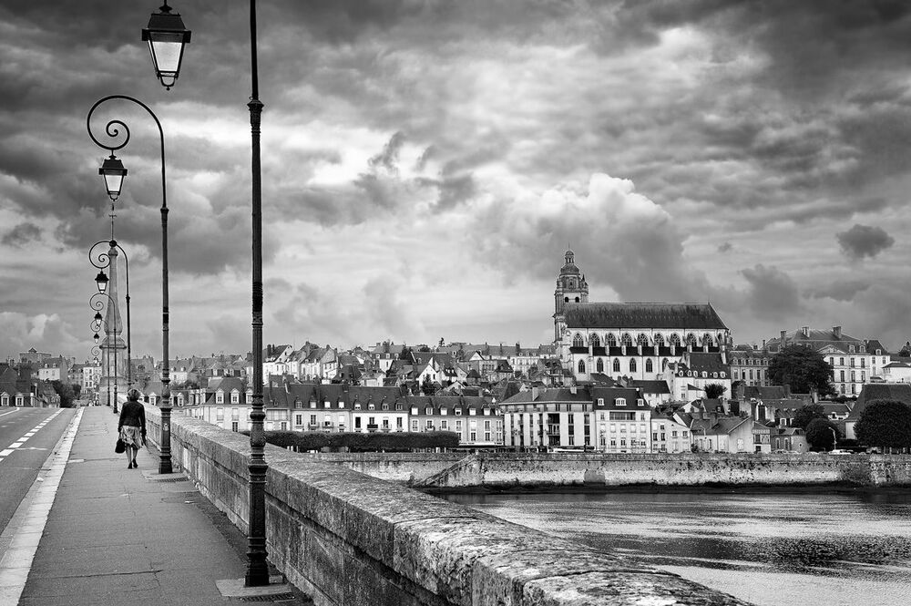 The medieval city of Blois with the Saint-Louis cathedral on a calm afternoon. Only this lady on her way home across the bridge over the Loire river.