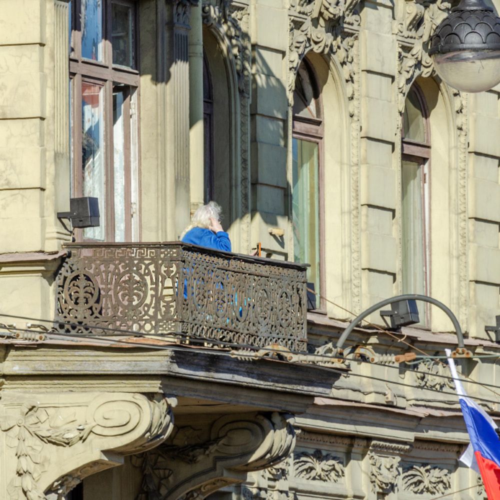 Невский проспект. Женщина на балконе держит в руке фотографию в рамке...