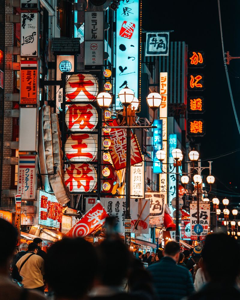 An atmospheric night shot in Dotonbori, where a traditional paper lantern and vibrant neon signs create a colorful composition.