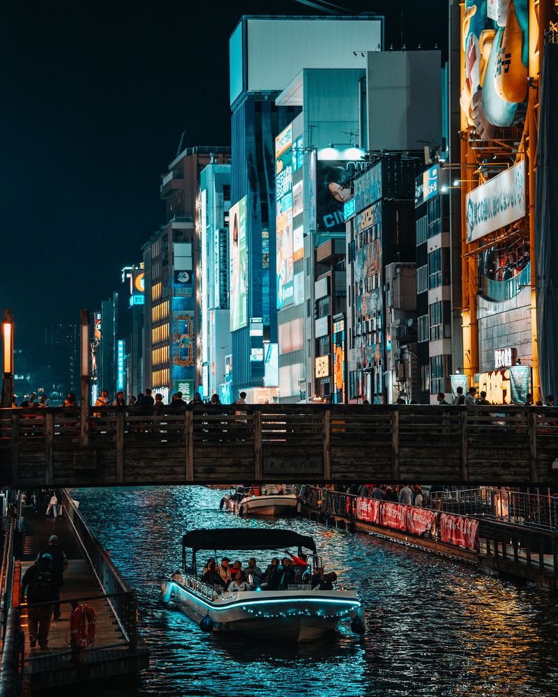An atmospheric night shot in Dotonbori, where a traditional paper lantern and vibrant neon signs create a colorful composition.