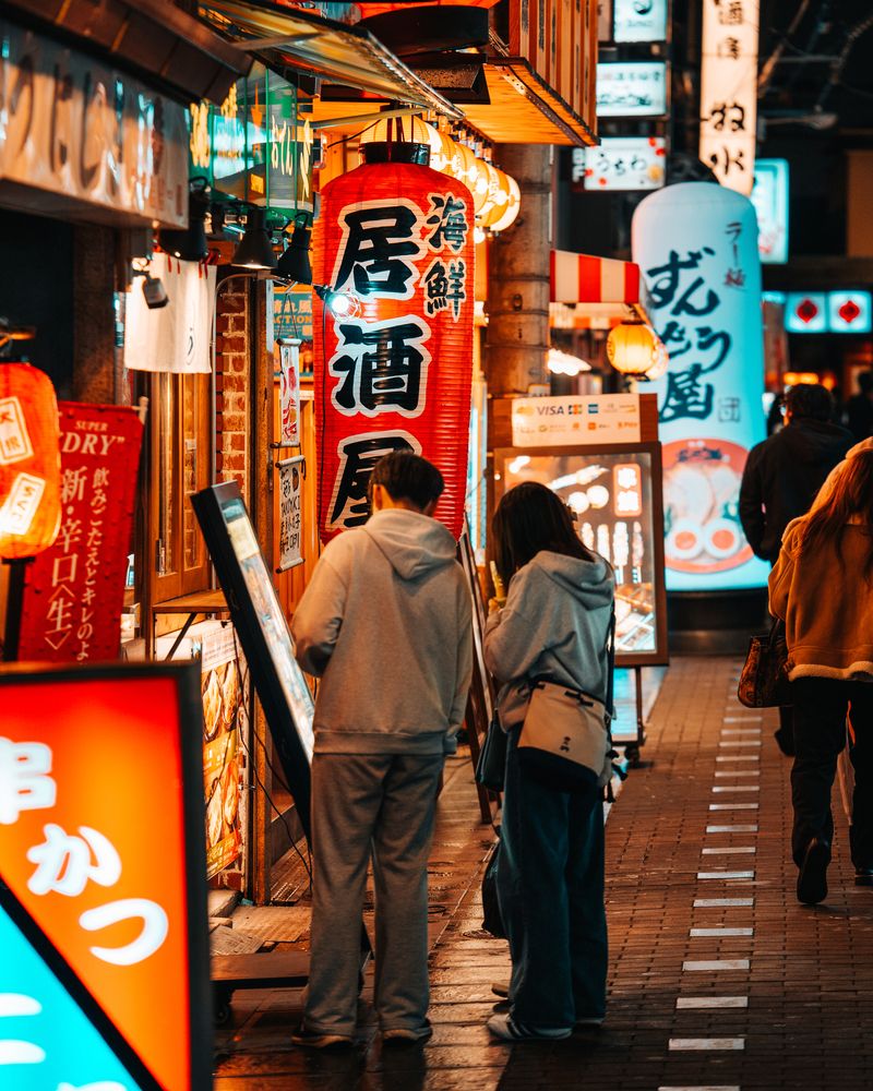 An atmospheric night shot in Dotonbori, where a traditional paper lantern and vibrant neon signs create a colorful composition.