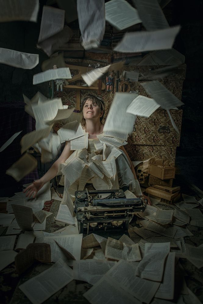 A writer types intensely while pages fly around them, capturing the chaos and energy of the creative process.