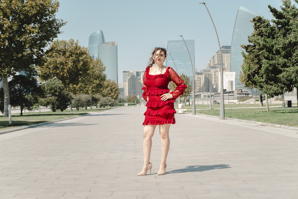A young woman posing confidently in a modern urban environment, showcasing contemporary fashion, natural beauty, and a vibrant city lifestyle with stylish architecture in the background.