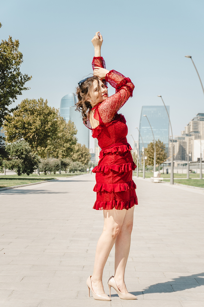 A young woman posing confidently in a modern urban environment, showcasing contemporary fashion, natural beauty, and a vibrant city lifestyle with stylish architecture in the background.