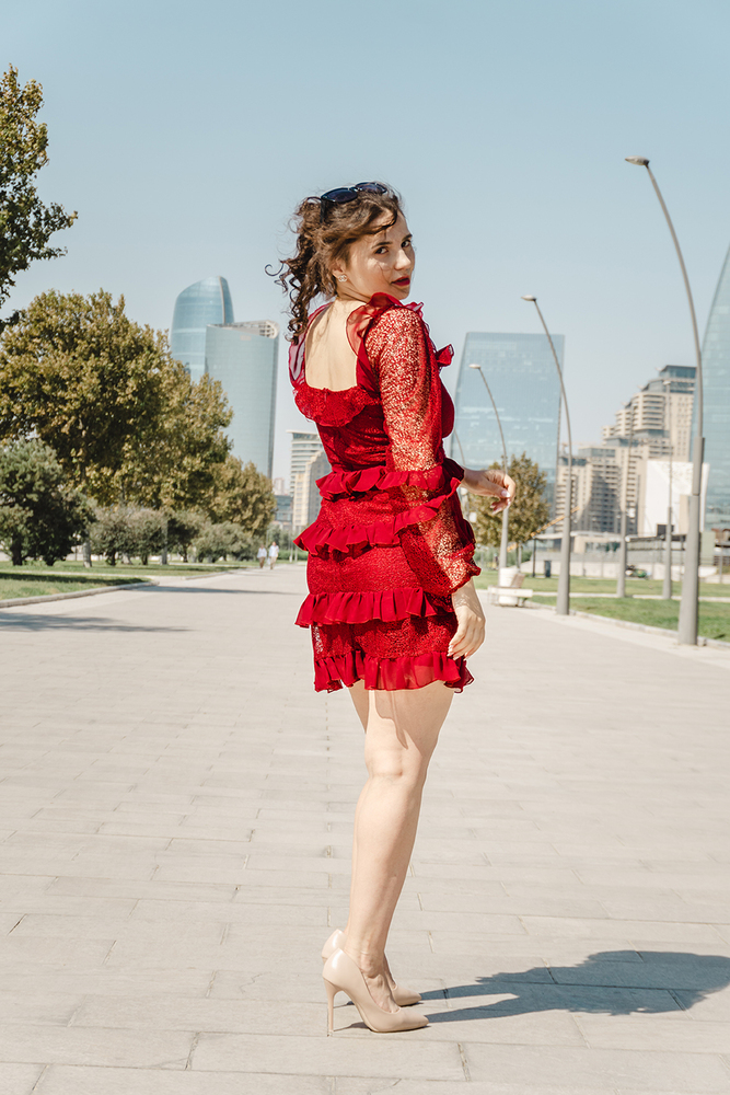 A young woman posing confidently in a modern urban environment, showcasing contemporary fashion, natural beauty, and a vibrant city lifestyle with stylish architecture in the background.