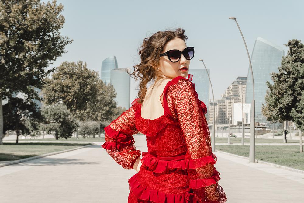 A young woman posing confidently in a modern urban environment, showcasing contemporary fashion, natural beauty, and a vibrant city lifestyle with stylish architecture in the background.