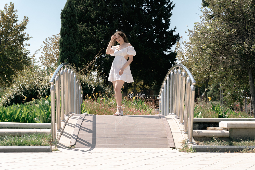 A young woman posing confidently in a modern urban environment, showcasing contemporary fashion, natural beauty, and a vibrant city lifestyle with stylish architecture in the background.
