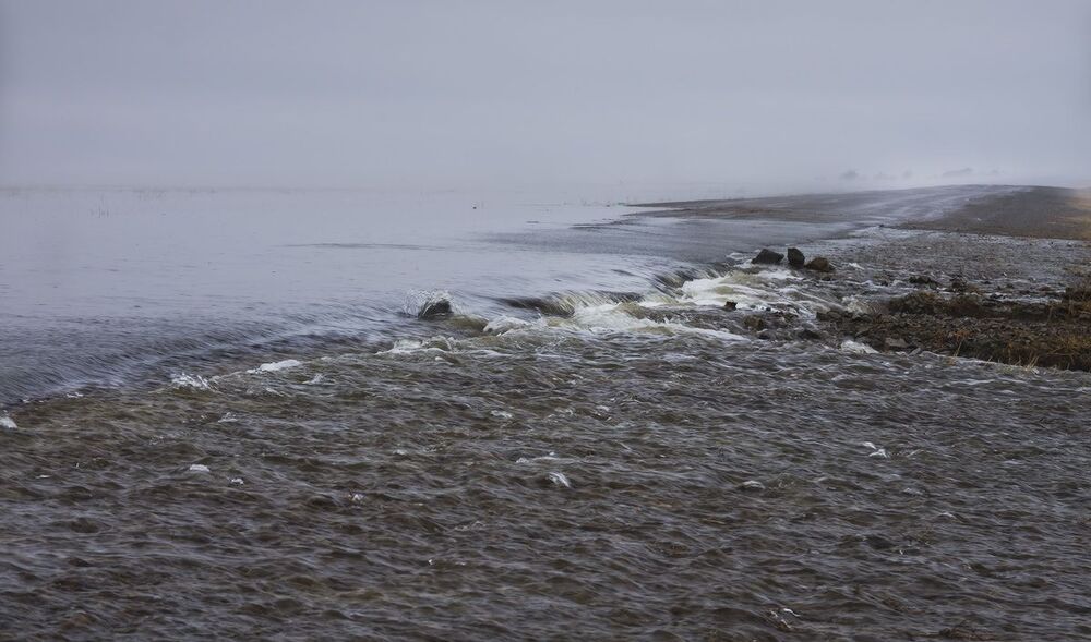 В нескольких местах вода пошла в наступление, переливаясь через дорогу и размывая последнюю.