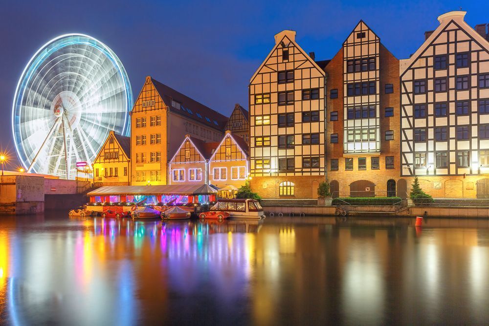 Ferris wheel with water reflection at Trade fair St Dominic in Old Town of Gdansk at night, Poland