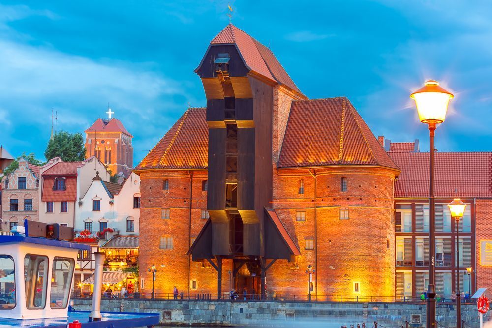 Old harbour crane and city gate Zuraw in old town of Gdansk at night, Poland