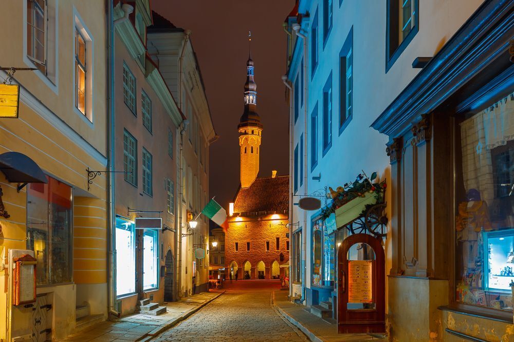 Narrow street illuminated of Old Town at night, City Hall on the background, Tallinn, Estonia