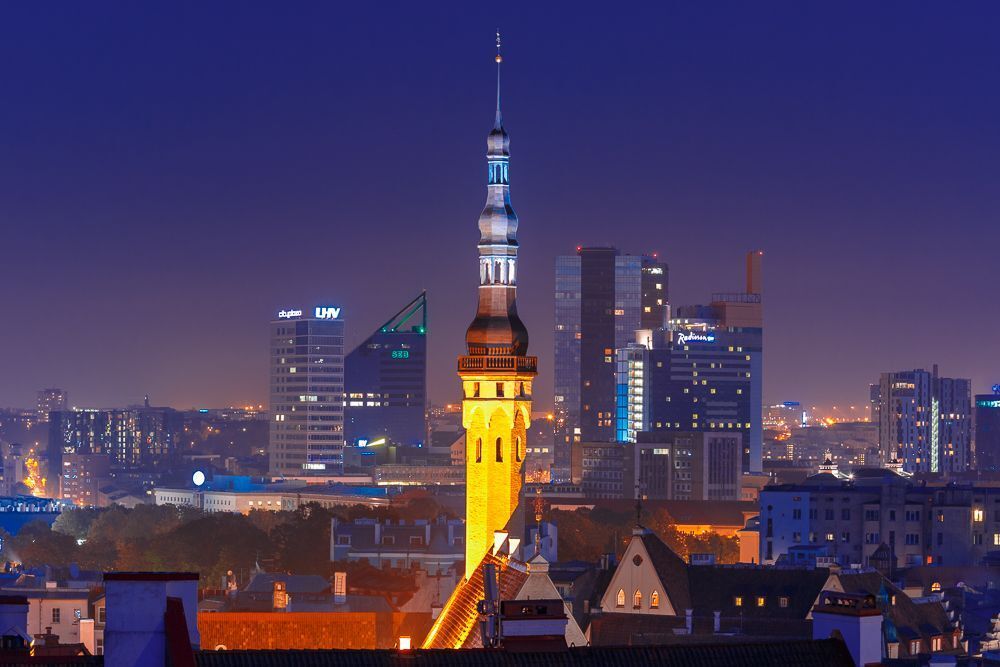 Night aerial cityscape with old town hall spire and modern office buildings skyscrapers in the background in Tallinn, Estonia