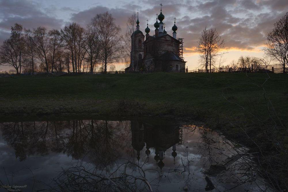 Ораньжевый закат, вид с отражением в маленьком пруду от алтарной части храма
