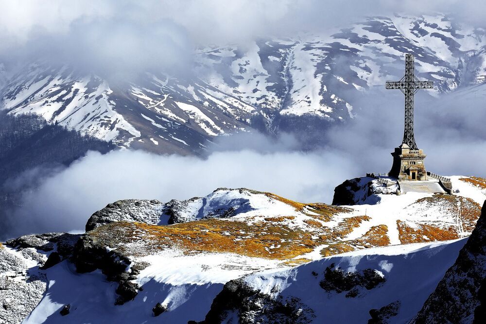 The Heroes' Cross is a monument built between 1926 and 1928 on Caraiman Peak at an altitude of 2,291 m located in Romania, in the Bucegi Mountains of the Southern Carpathians. It has a height of 36 metres (118 ft) and the nearest town is Buşteni. The name of the monument is "The Heroes' Cross", but it is popularly known as the "Cross on Caraiman". The Heroes' Cross is located in the saddle of the Caraiman Mountains, on the slope to the Seacă Valley at an elevation of 2,291 metres (7,516 ft); it is unique in Europe, both by the location's altitude and by the monument's size. The cross itself has a height of 28 metres (92 ft) and two arms of 7 metres (23 ft) each. The monument was the tallest structure in the world situated at such an altitude. The width of the vertical pole is 2 metres (7 ft), the horizontal arms have a length by spindle pole of 7 metres (23 ft), and a square cross section with sides of 2 metres (7 ft). The cross is made out of steel profiles and is mounted on a pedestal of concrete clad with stone 7.5 metres (25 ft) high. Inside the pedestal there is a room that originally housed the electric generator that powered the 120 light bulbs of 500 W each located on the perimeter of the cross.