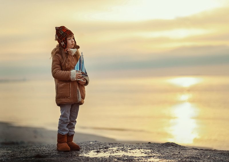 море вечер зима побережье девочка детство теплая одежда грусть кораблик игрушка штиль мечтательница фото превью