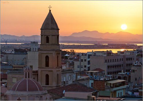Вид на Кальяри с заходящим за горы солнцем