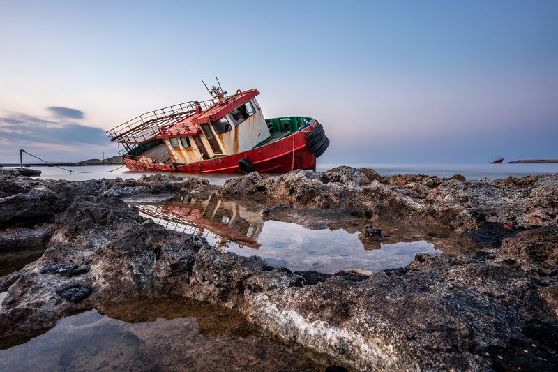 Greece; Kithera; Kithira; blue; boat; coast; dusk; old; red; reflection; rock; rusty; sea; shipwreck; sky; stone; stranded; water Red Boat Stranded on Kythera island фото превью