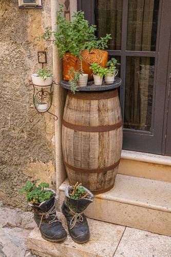 Цветы в старых ботинках и деревянная бочка в борго Caserta Veccia в Италии