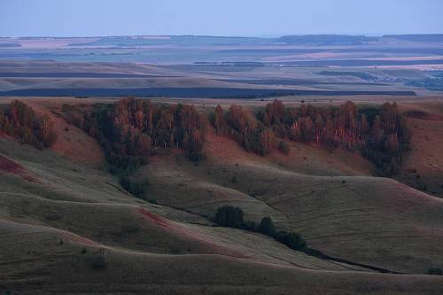 Багровый свет заката на волнах холмов/