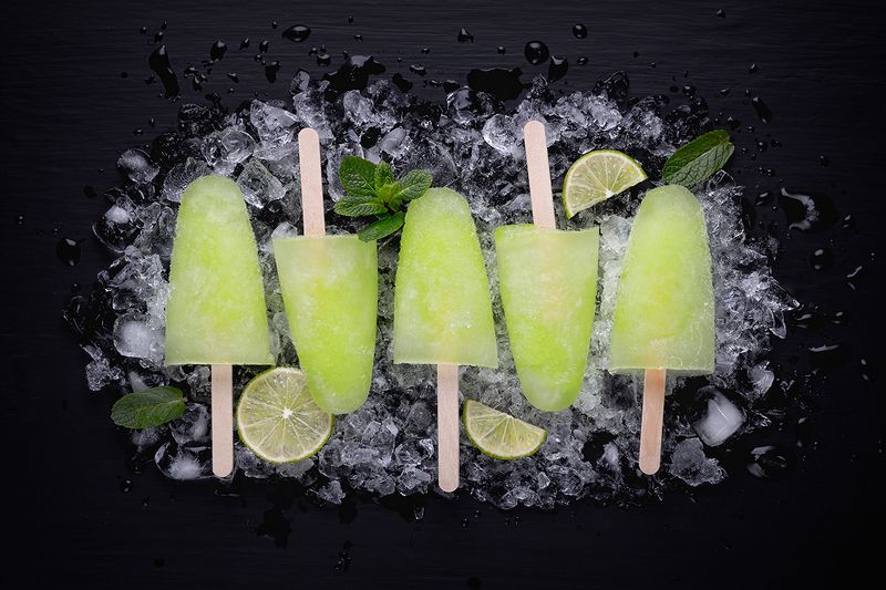 ice; cream; stick; healthy; popsicle; fruit; mojito; cold; refreshing; lime; lollipop; green; ice cream; mint; juice; homemade; pop; rustic; sorbet; fresh; frozen; cool; colourful; exotic; menu; tropical; vegan; vintage; lemon; yellow; sherbet; horizontal Homemade popsicles with lime juice and mint, mojito fruit ice on a black wooden table. фото превью