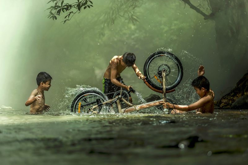 #summer. #Bicycle #Candid #Child #Children Only #Color Image #Day #Horizontal #Outdoors #People #Photography #Pre-Adolescent Child #Real People #Sunlight #Thai culture #Three Boys #Togetherness #Tradition #Transportation #Two People #Wading #Washing #Wate The boys are washing bicycle playfully River Near Home фото превью