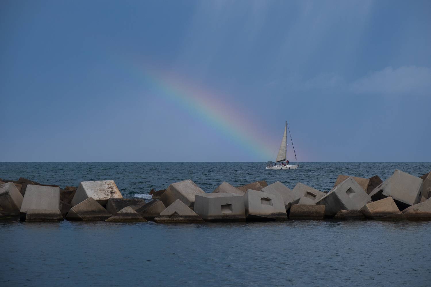 barcelona coast, coastal beauty, concrete block division, sailboat, rain and rainbow, nature and urban charm, mesmerizing scene, barcelona maritime scenery, sky, captivating composition, vibrant coastal panorama, natural wonders of barcelona, urban coasta, Druz Denys