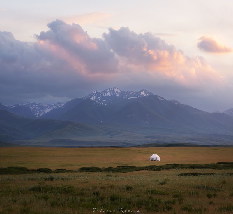 Закатное солнце опускается за гору, освещая своими лучами долину и одинокую юрту....Кыргызстан фото превью