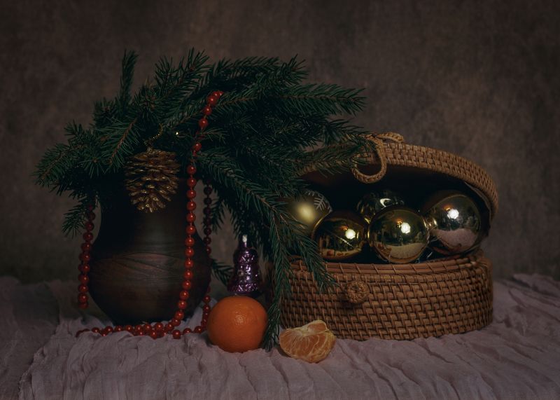 натьрморт, новогодний натюрморт, еловая ветка, шишка, плетеная шкатулка, елочная игрушка, мандарин, оранжевый, красный, красные бусы, глиняный горшок, долька мандарина, коричневый фон Долька мандаринки фото превью