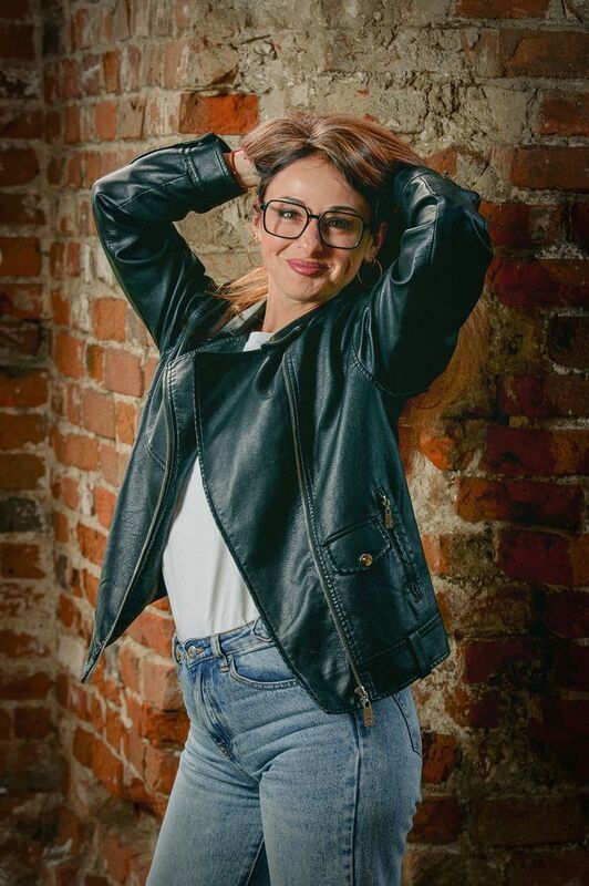 Красивая девушка в кожаной куртке на фоне кирпичной стены. фото превью