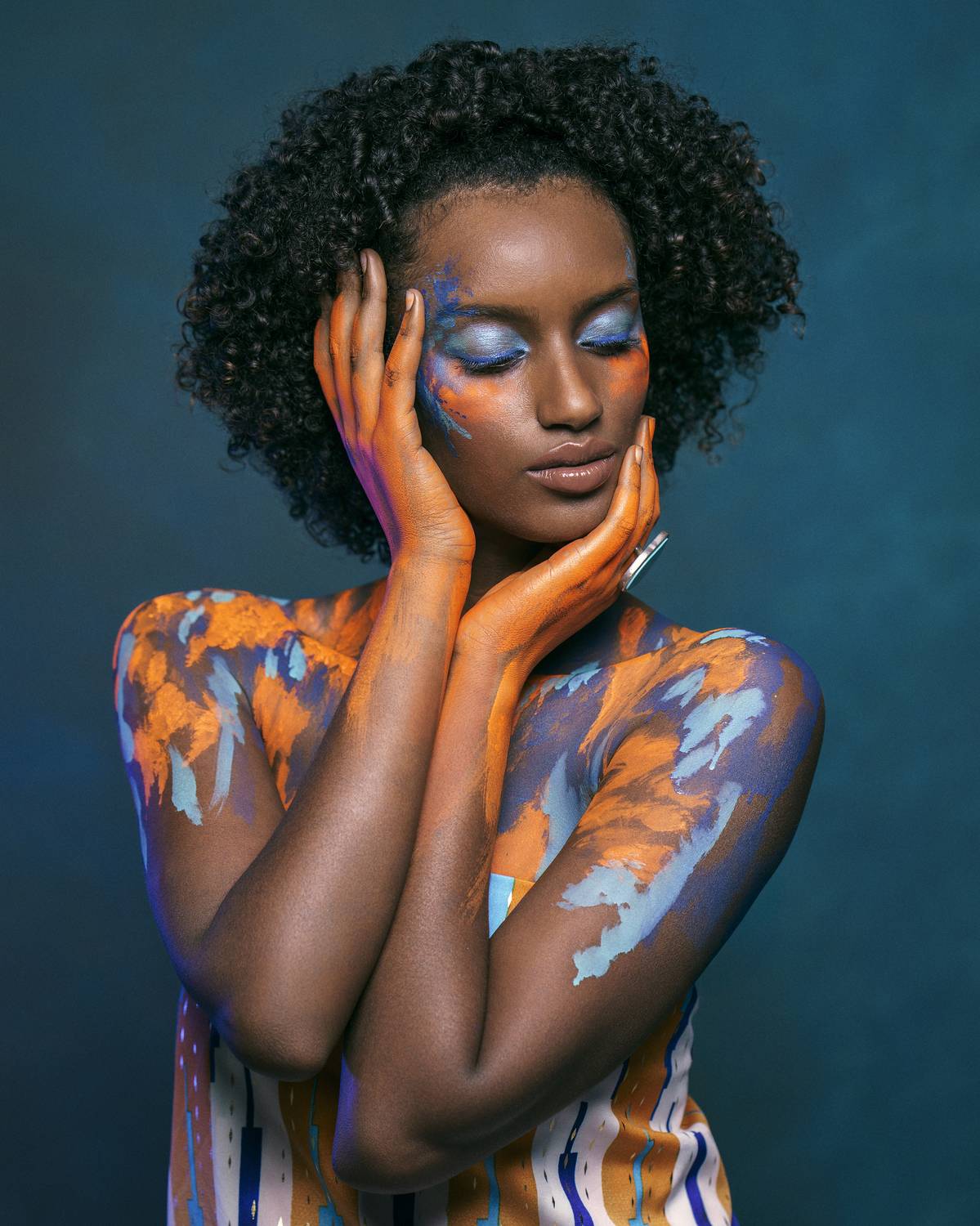 african beauty, amber accents, artistic portrait, blue eyeshadow, body art, bold colors, color harmony, creative makeup, curly hair, dark skin, ethnic style, exotic elegance, expressive hands, fine art, front view, painted body, vibrant colors, Alex Tsarfin