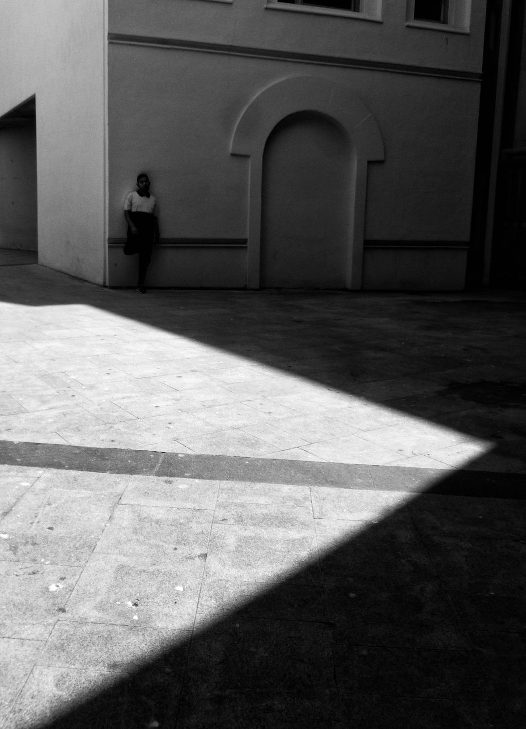 monochrome, black_and_white, bnw, high_contrast, street_photography, fine_art, minimalism, abstract, candid, light_and_shadow, shadows, sunlight, geometric_shapes, diagonal, line, architecture, courtyard, wall, archway, solitude, lonely, person, figure, u, Sandoval Carlos