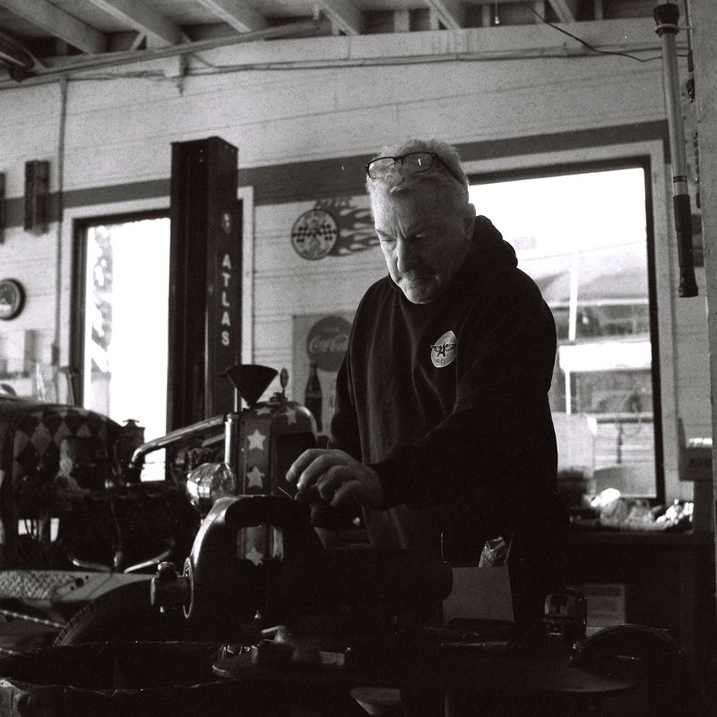 Niles, Freemont, California (2023)    He stands in his element—garage light streaming through dust and decades, hands ready for the work that waits in the vice. Through Lomography\\\'s grain, this workshop becomes cathedral: where metal meets patience, wher Niles фото превью