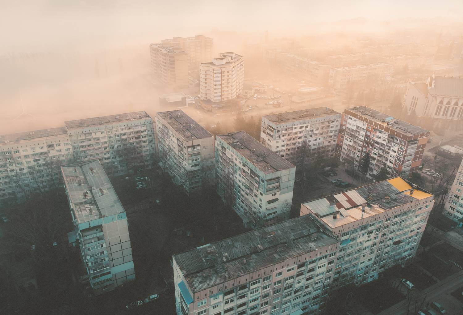 город, урбан, городской пейзаж, спальный район, панельные дома, многоэтажки, архитектура, бетон, двор, крыши, вид сверху, дрон, аэрофото, туман, дымка, пыль, смог, рассвет, утро, оранжевый свет, холодные тона, атмосфера, минимализм, геометрия, индустриаль, Олег Сухенко