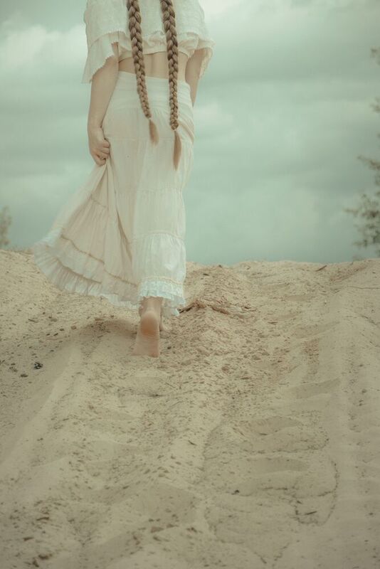 Косы, песок, длинная юбка, тучи, идущая девушка, белое платье  фото превью