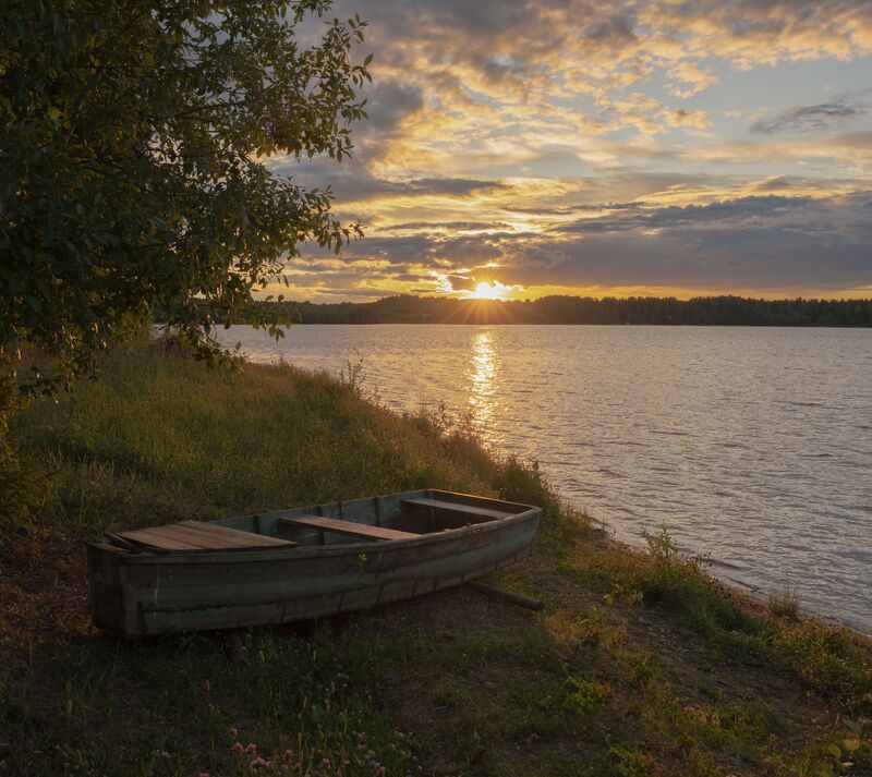 Яркий закат у забытой лодоки фото превью