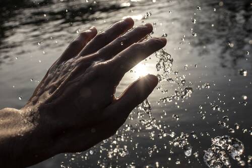 Hands and River Water at Sunset