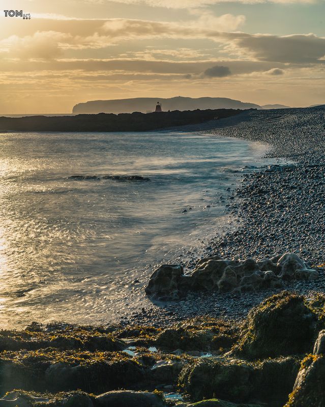 sea motion uk england water blue sunset waves sun lighthouse stone rocks rock green blue yellow clouds cloud sky  \