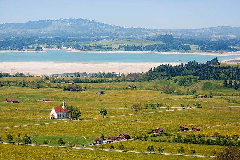 фотография с полем одуванов, дорожками, озером, церквушкой Colomanskirche и одиноким дельтапланеристом фото превью