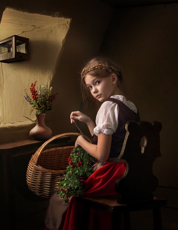 Young girl weaves a wreath at the window фото превью