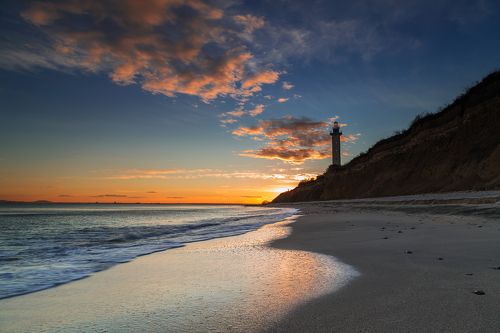 Lighthouse on the rocks at sunset