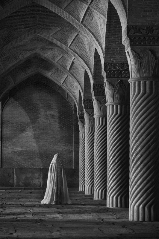 A woman standing between old columns фото превью